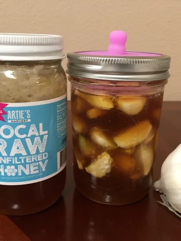 jar of fermented honey garlic with jar of local raw honey