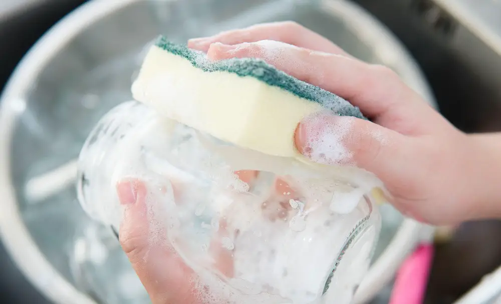 women washing glass jar with dishwasher